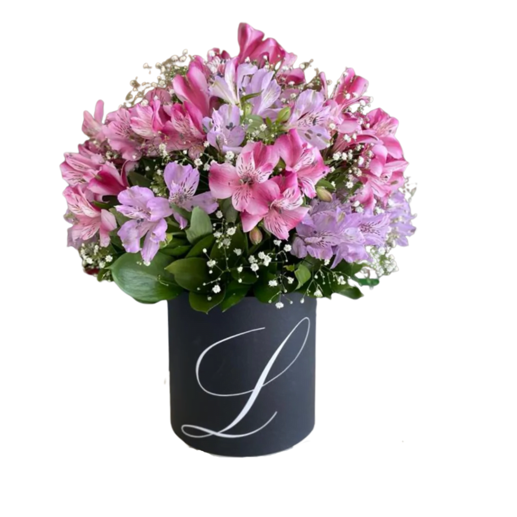 Box Charlote é um Arranjo de flores em box preto com a letra L, composto por astromélias rosas e lilases com folhagens verdes e gypsophila branca