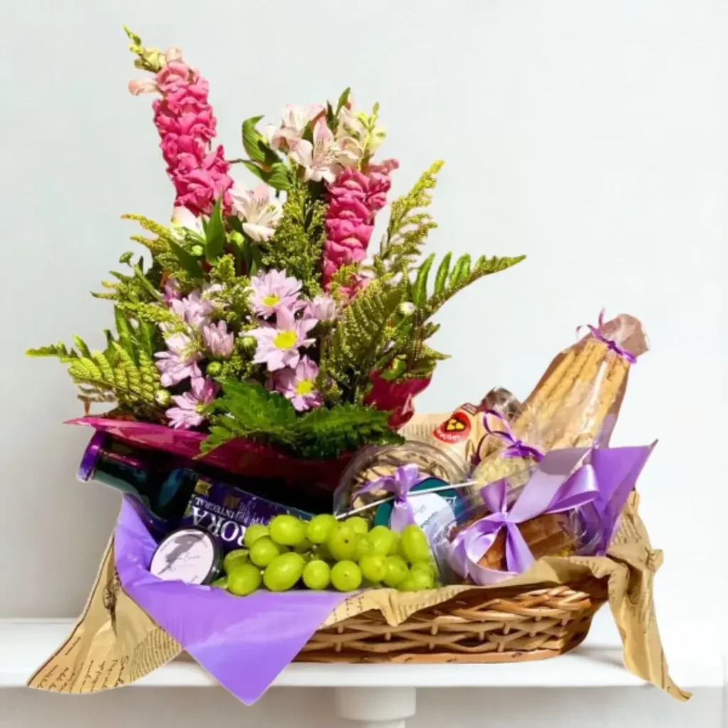 Cesta de Café Lara Cesta de presente com flores, frutas, suco e produtos gourmet decorada em tons de roxo.