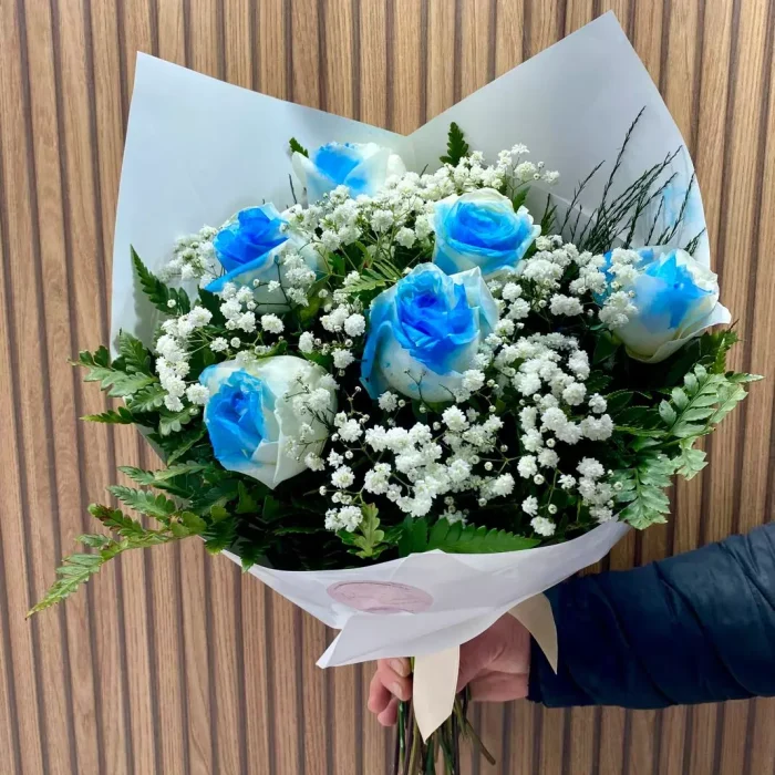 Buquê de rosas blue com mosquitinho e folhagens, embalado em papel branco elegante com laço decorativo.
