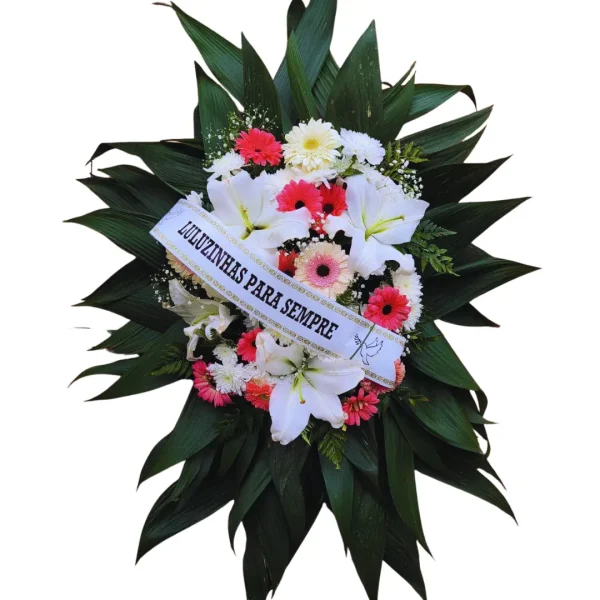 Coroa de Flores - U- CO054 com lírios brancos, gérberas rosa e brancas, crisântemos e folhagens verdes, com faixa personalizada.