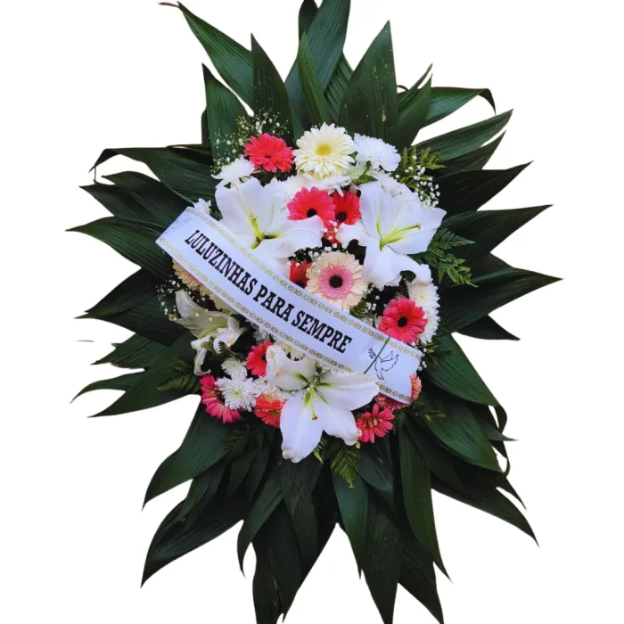 Coroa de Flores - U- CO054 com lírios brancos, gérberas rosa e brancas, crisântemos e folhagens verdes, com faixa personalizada.